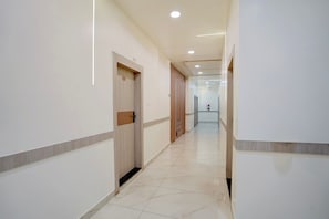 Un pasillo limpio y bien iluminado con una puerta de madera marcada con el número 102, que da a una habitación.