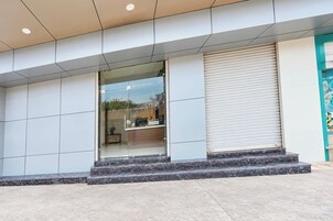 A modern building with a glass entrance, a closed shutter door, and a tiled facade.