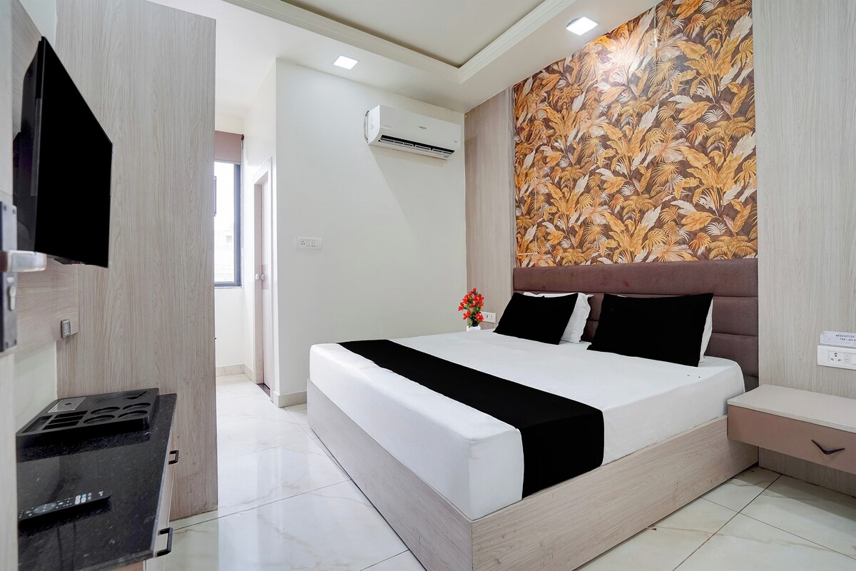 A modern hotel room with a large bed, a flat-screen TV, and a decorative wall.