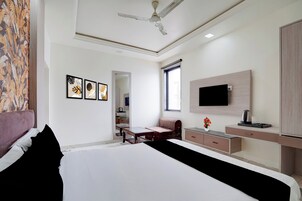 A hotel room with a bed, a desk, a chair, a television, and a ceiling fan.