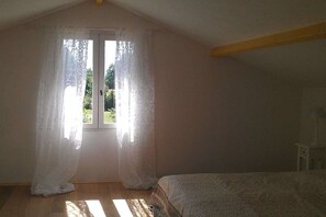 A bedroom with a bed, a window with curtains, and a wooden floor. - Holiday home with 2 bedrooms (Biscarrosse)