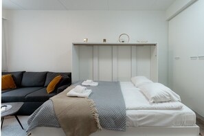 A modern bedroom with a bed, a sofa, and a small table. - Levi South Studio 1 and 2, Sauna By Lapland Host (Kittilä)