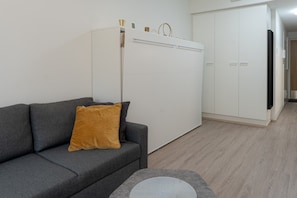 A modern living room with a grey sofa, a mustard-colored pillow, a white wardrobe, and a grey rug. - Levi South Studio 1 and 2, Sauna By Lapland Host (Kittilä)