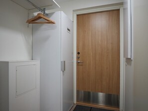 A room with a wooden door, a white wall, a radiator, and a hanging coat rack. - Levi South Studio 1 and 2, Sauna By Lapland Host (Kittilä)