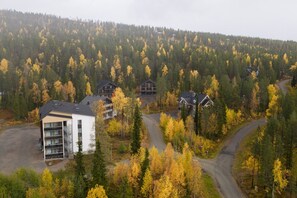 A modern building with multiple floors, surrounded by a forested area with autumn-colored trees. - Levi South Studio 1 and 2, Sauna By Lapland Host (Kittilä)