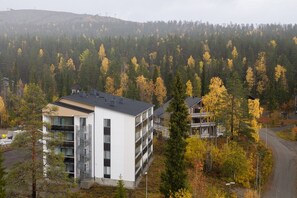A modern building with multiple floors, surrounded by a forest with autumn foliage. - Levi South Studio 1 and 2, Sauna By Lapland Host (Kittilä)