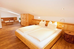 Ein Schlafzimmer mit einem großen Bett, Holzwänden, einer Bank und einem kleinen Tisch.