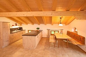 A kitchen with wooden beams, a central island, and a dining area with benches. - Holiday apartment with 2 bedrooms (Bernau)