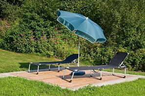 A wooden deck with two lounge chairs and a blue umbrella. - Holiday apartment with 2 bedrooms (Bernau)