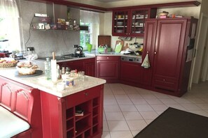 A kitchen with red cabinets, a countertop, and various kitchen appliances.