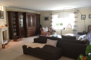 A living room with a sofa, a fireplace, a bookshelf, and a dining area with a table and chairs.