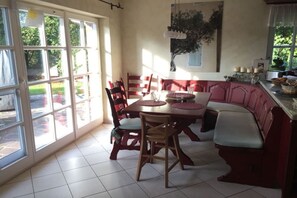A dining area with a table and chairs, a bench, and a view through large windows.