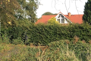 A house with a red roof, surrounded by dense greenery and trees. - Cabin in Friedeburg with swimming pool (Friedeburg)