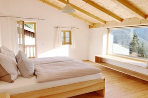 Quarto com cama de madeira, janela com vista para o exterior e teto de madeira.