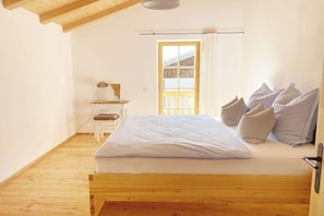 Ein Schlafzimmer mit einem hölzernen Bett, einem Schreibtisch und einem Fenster mit Vorhängen.