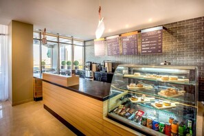 A modern coffee shop with a counter, menu boards, and a display case with pastries and drinks. - Ewaa Express Hotel - Gaber Riyadh (Riyadh)