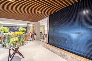 A lobby with a wooden ceiling, a blue shuttered wall, and a table with floral arrangements. - Ewaa Express Hotel - Gaber Riyadh (Riyadh)