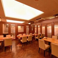 Un salón de conferencias con mesas y sillas de madera, techo con tragaluces y diseño moderno.