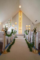 Interior de iglesia con bancas, un pasillo central y un altar decorativo.