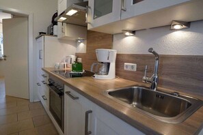 Een moderne keuken met een roestvrijstalen spoelbak, een ingebouwde oven en een koffiezetapparaat.