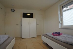 A bedroom with a bed, a wardrobe, and a window. - Holiday apartment with 2 bedrooms (Norddeich)