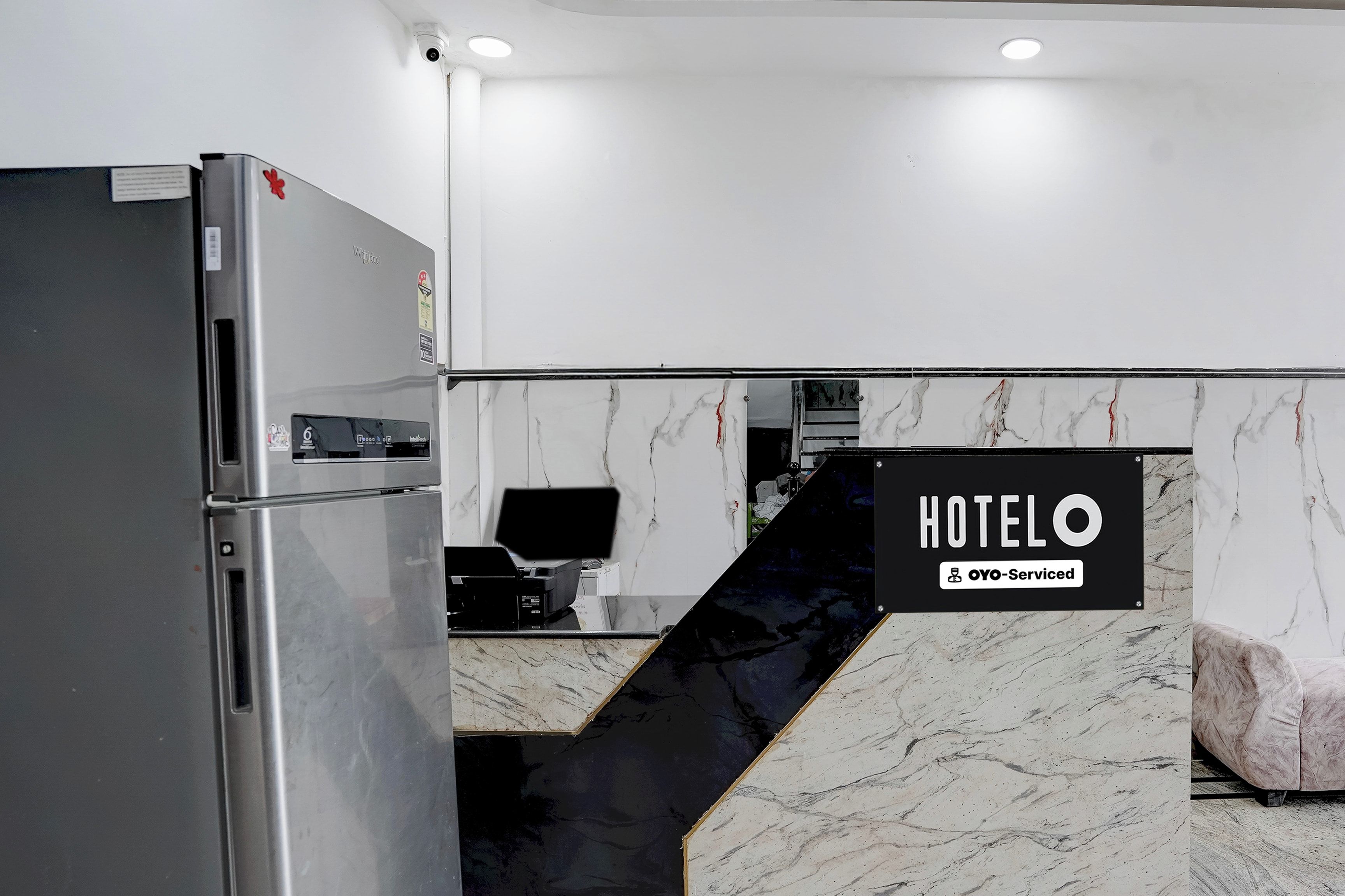 Una cocina moderna con refrigerador, cafetera y un letrero que indica un servicio de hotel.