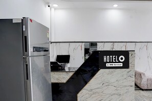Una cocina moderna con refrigerador, cafetera y un letrero que indica un servicio de hotel.