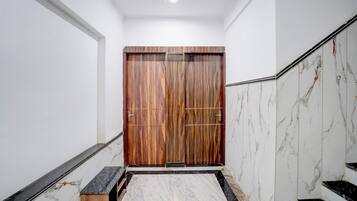 Un pasillo con puerta de madera, paredes y suelo de mármol.