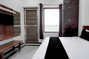 Habitació d'hotel amb un llit, una panxa, un armari i una porta que dona a un balcó.