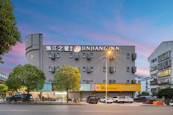 A hotel with a prominent sign, multiple floors, and a parking area in front. - Jinjiang Inn Select (Shanghai)