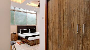 A bedroom with a bed, a wooden wardrobe, a window with blinds, and a ceiling fan.