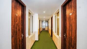 A hallway with wooden doors, a green carpet, and a white wall.