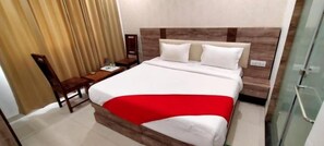 A hotel room with a bed, a desk, and a chair. - Hotel Almond (Zirakpur)