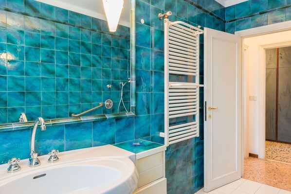 A bathroom with a bathtub, a white towel rack, and a shower area. - Ca Magno (Venice)
