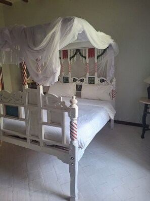 A bed with a canopy, white headboard, and striped pillows.