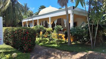 A building with a dome roof, surrounded by lush greenery and palm trees.