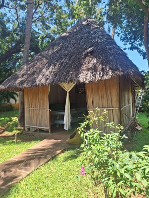 A thatched-roof hut with a simple entrance and a pathway leading to it.