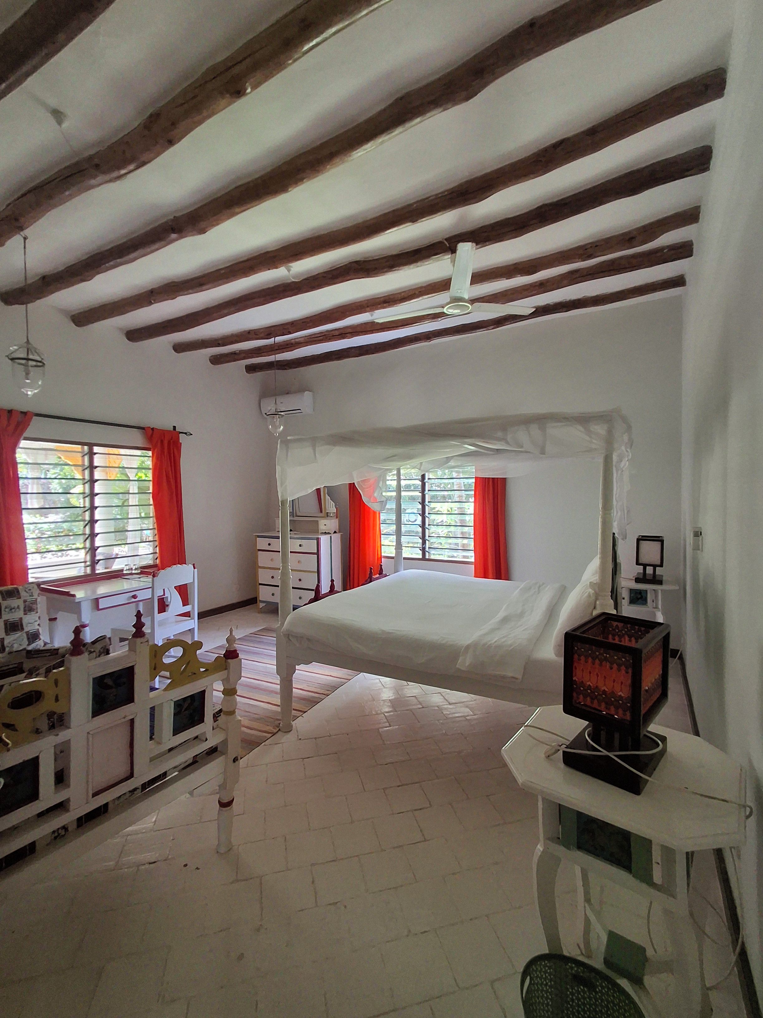 Une chambre à coucher avec un lit, un bureau, une chaise et une fenêtre avec des rideaux.