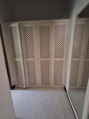 A room with a tiled floor and a set of white louvered doors.