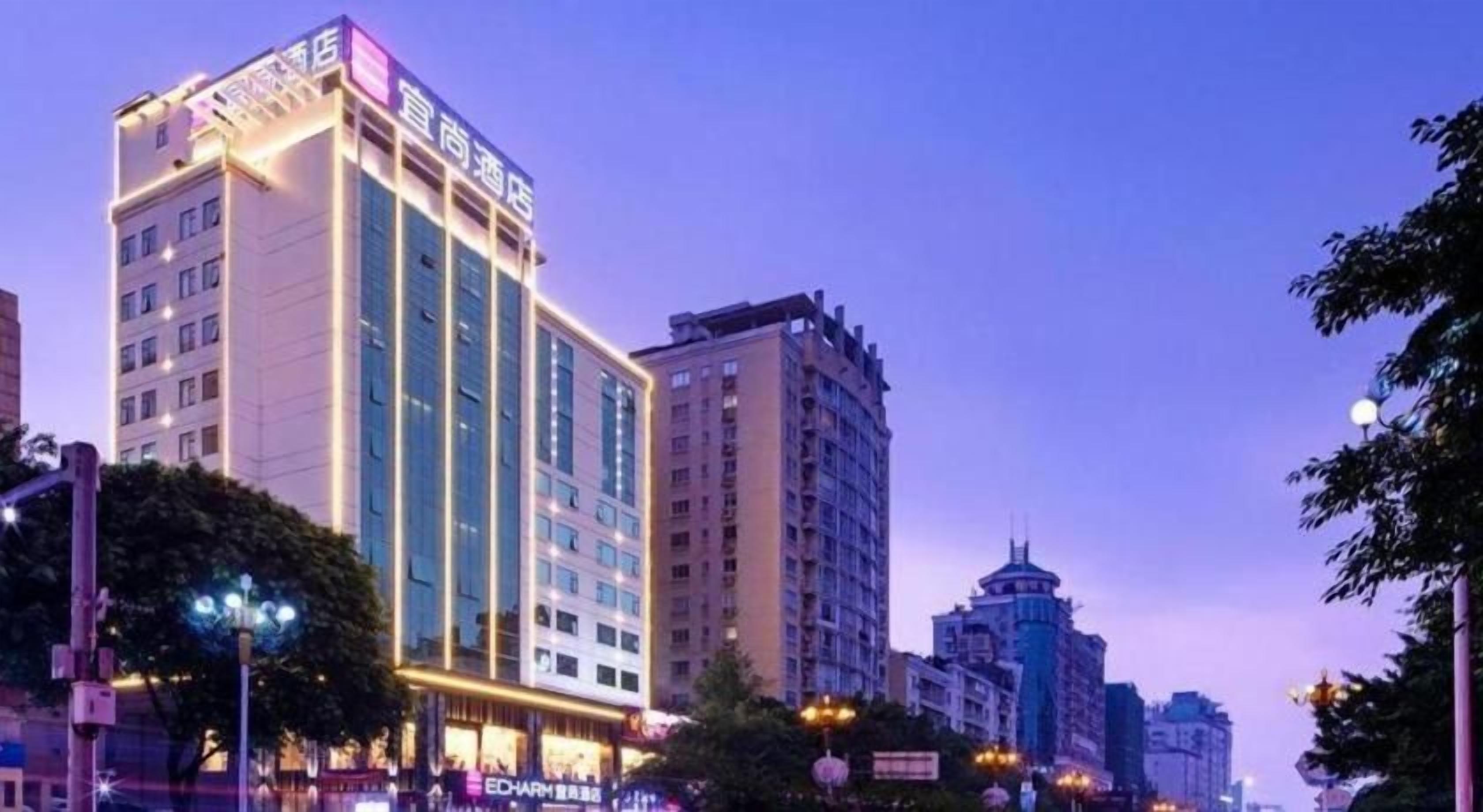 A multi-story hotel with a prominent sign, surrounded by other buildings and street lights.