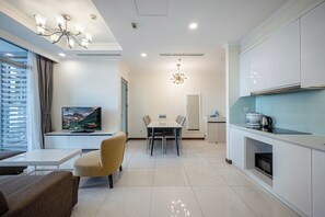 Ein modernes Wohnzimmer mit Flachbildfernseher, Esstisch mit Stühlen, einer Couch und einer Küchenzeile mit Schränken und Geräten.