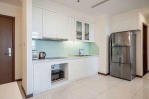 Eine moderne Küche mit weißen Schränken, einem Edelstahlkühlschrank und einem eingebauten Backofen.