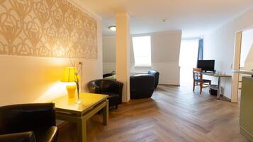 A living room with a dining area, a TV, and a desk.