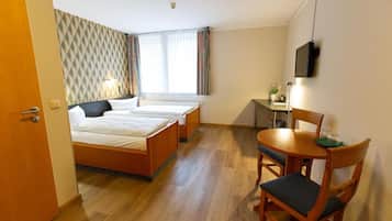 A hotel room with two beds, a desk, a chair, and a TV.