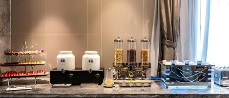 Una zona de cocina con equipo para preparar café, frascos de granos de café y una cafetera.