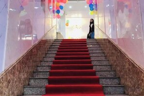 Una escalera con alfombra roja que conduce a un espacio interior luminoso.