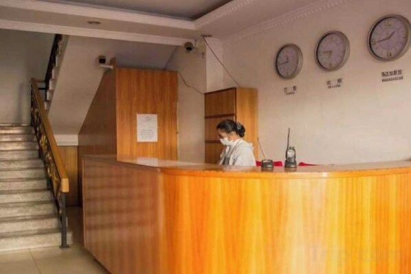 Una recepción con detalles de madera, una escalera a la izquierda y tres relojes en la pared.