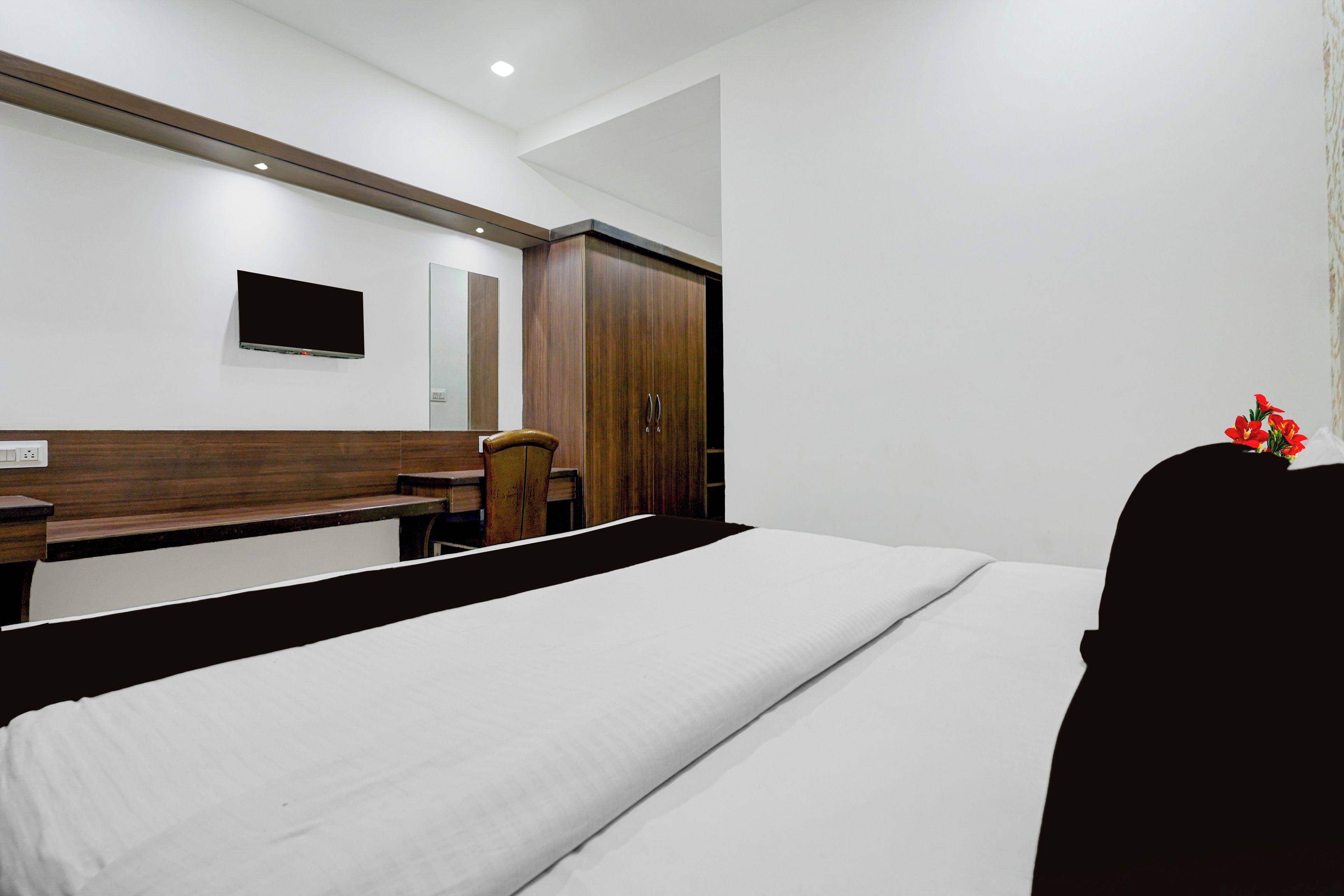 A hotel room with a bed, a desk, a chair, a wardrobe, and a television.