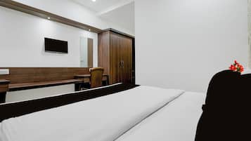A hotel room with a bed, a desk, a chair, a wardrobe, and a television.
