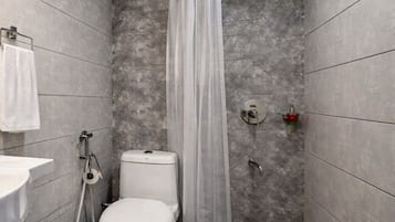 Een kleine, moderne badkamer met toilet, douche en wastafel.